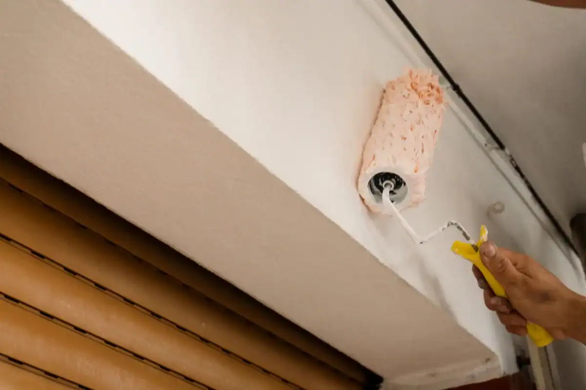 Close-up of roller applying paint to exterior soffit and trim